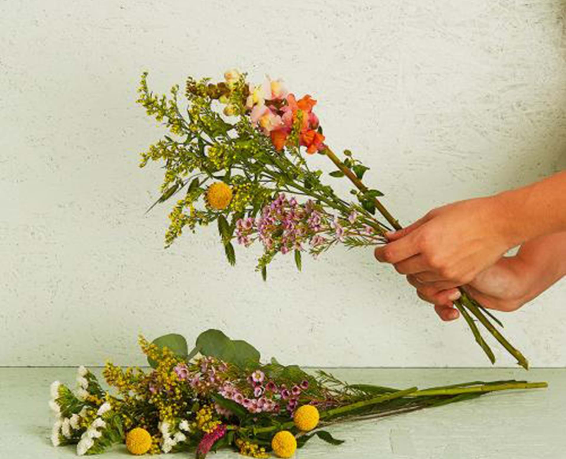 Hænder der holder mobiltelefon og tager billede af blomster